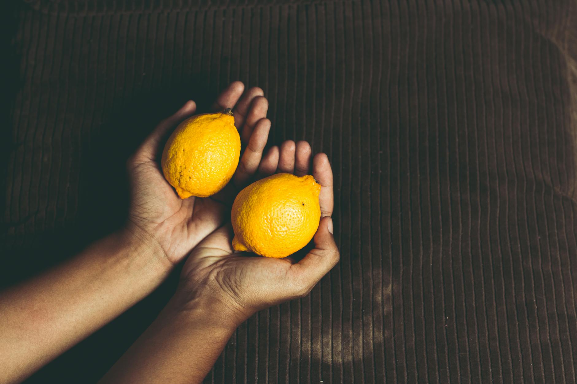 A yellow lemon vibrator surrounded by fresh lemons on a clean surface, representing gentle postpartum pleasure