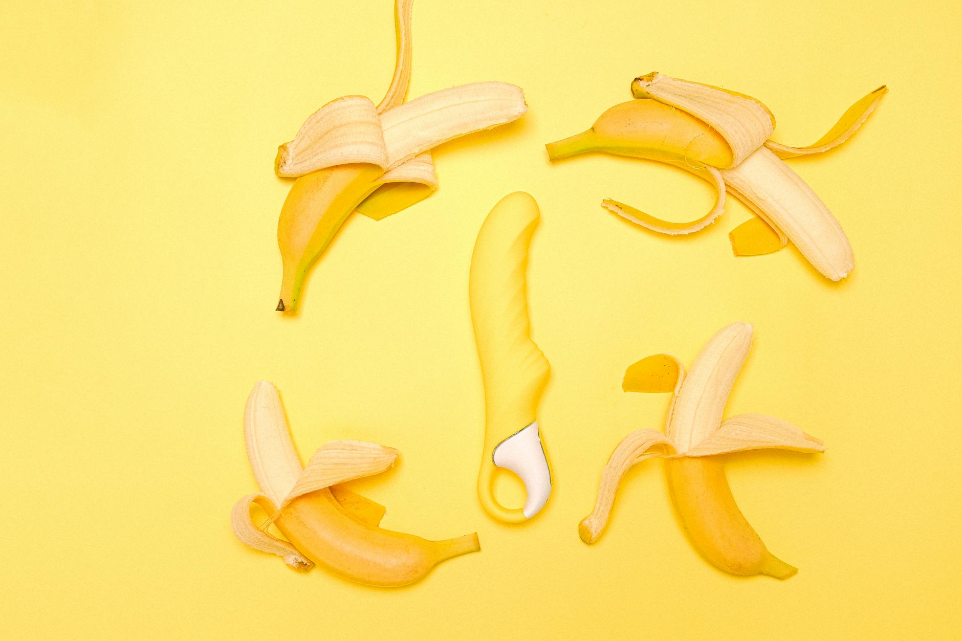 Yellow silicone lemon vibrator arranged with fresh lemons on a bright background