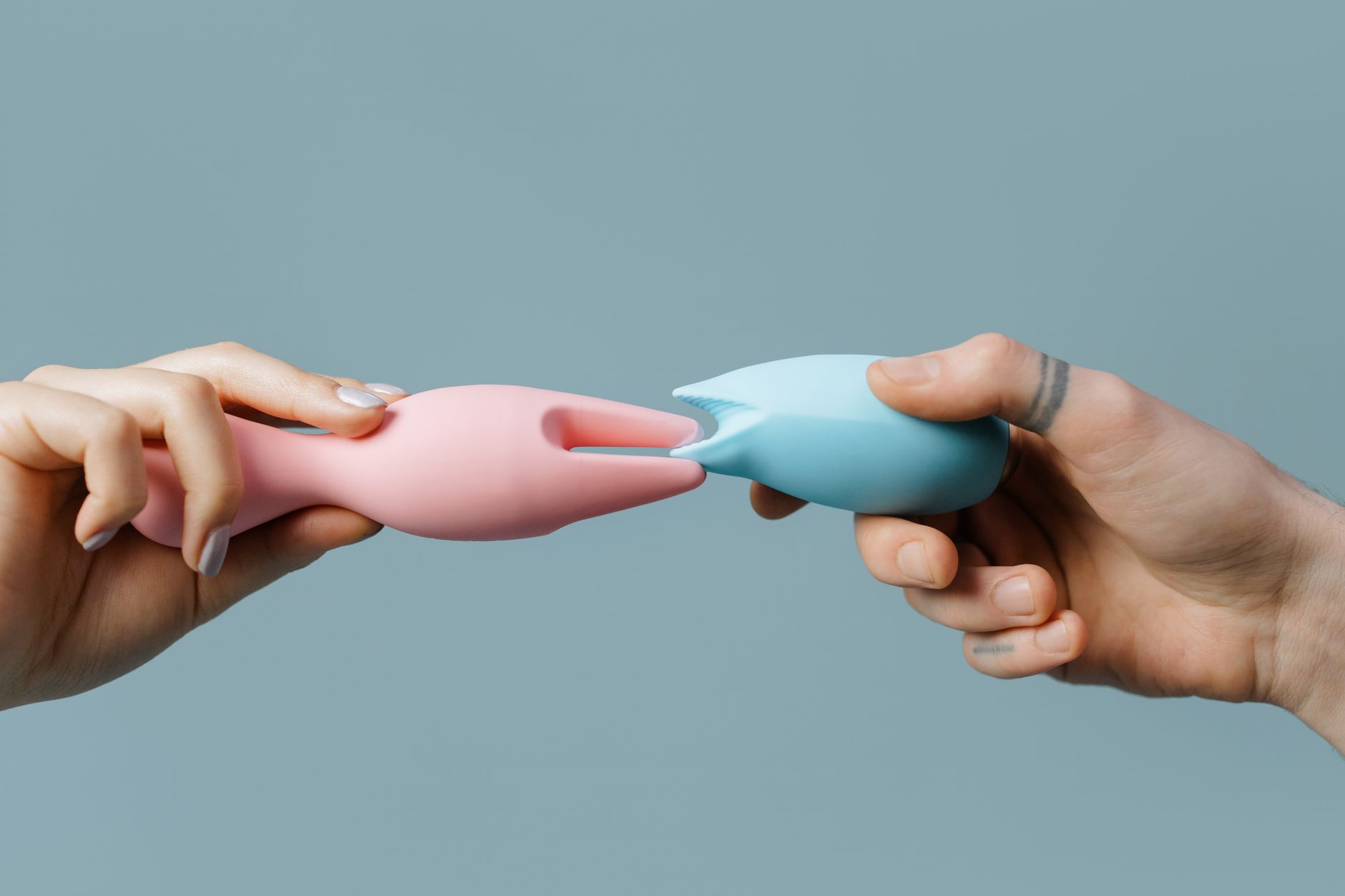 Woman holding two colorful clitoral vibrators, showing different intensity options